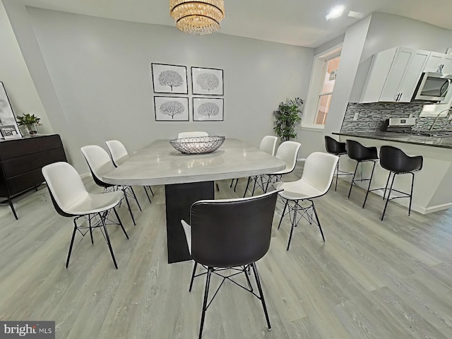 134 N Hobart St, Philadelphia, PA 19139 - dining area with light wood finished floors, a chandelier, and baseboards