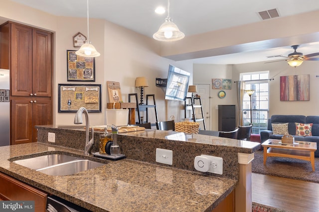 7136 Daniel John Dr, Elkridge, MD 21075 - kitchen with open floor plan, wood finished floors, a ceiling fan, brown cabinetry, and hanging light fixtures