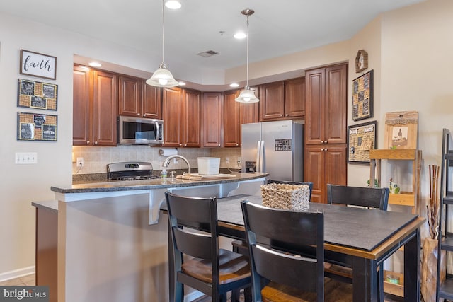 7136 Daniel John Dr, Elkridge, MD 21075 - kitchen featuring stainless steel appliances, backsplash, a breakfast bar area, hanging light fixtures, and dark stone countertops