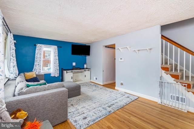 2410 Saint Clair Dr, Temple Hills, MD 20748 - living area featuring wood finished floors, a textured ceiling, baseboards, and stairs