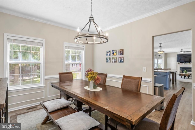 1104 Century Oak Dr, Fredericksburg, VA 22401 - dining space featuring wood finished floors, a chandelier, a textured ceiling, crown molding, and wainscoting