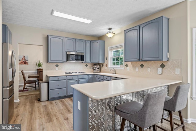 1104 Century Oak Dr, Fredericksburg, VA 22401 - kitchen featuring appliances with stainless steel finishes, a peninsula, a sink, a breakfast bar area, and light wood-style flooring