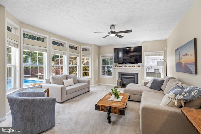 1104 Century Oak Dr, Fredericksburg, VA 22401 - carpeted living room with a ceiling fan, plenty of natural light, a glass covered fireplace, a textured ceiling, and baseboards