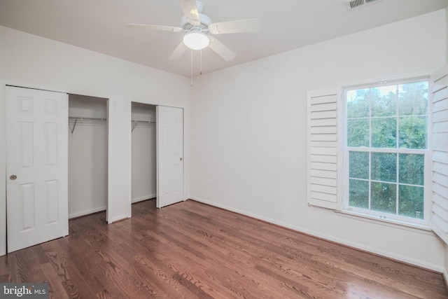 1421 Pickett Ct, Front Royal, VA 22630 - unfurnished bedroom featuring two closets, multiple windows, wood finished floors, and a ceiling fan