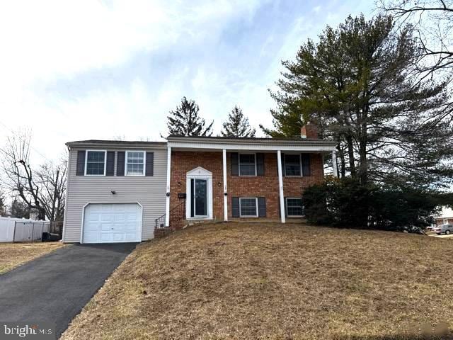 3 New Coach Ln, Willingboro, NJ 08046 - split foyer home with asphalt driveway, an attached garage, a chimney, and brick siding