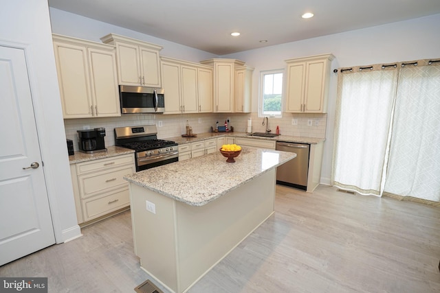 36063 Auburn Way, Millsboro, DE 19966 - kitchen featuring stainless steel appliances, cream cabinetry, a sink, light wood-style floors, and decorative backsplash