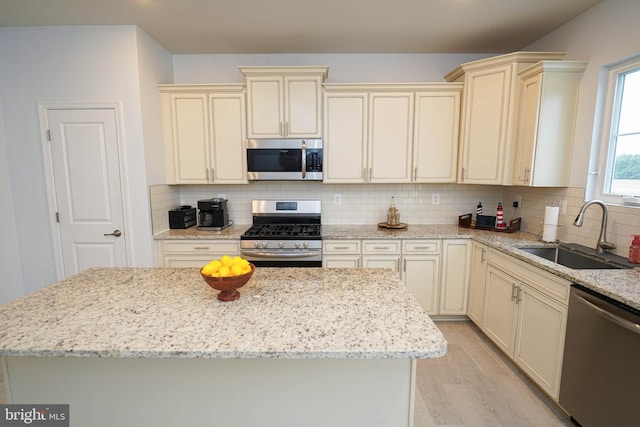 36063 Auburn Way, Millsboro, DE 19966 - kitchen featuring appliances with stainless steel finishes, cream cabinets, a sink, light wood finished floors, and tasteful backsplash