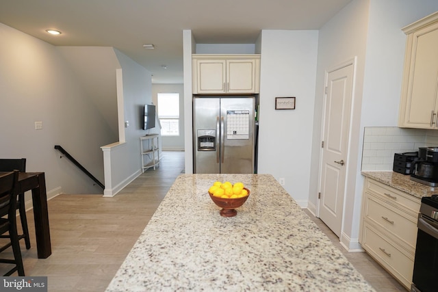 36063 Auburn Way, Millsboro, DE 19966 - kitchen with stainless steel fridge, cream cabinets, light wood-style floors, tasteful backsplash, and light stone counters
