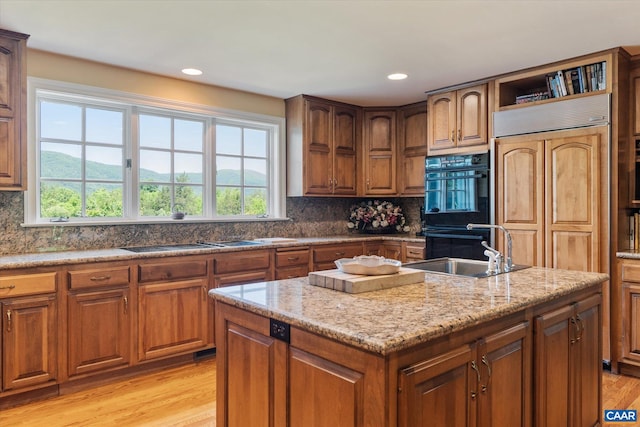 5190 Sugar Ridge Rd, Crozet, VA 22932 - kitchen with black appliances, a kitchen island with sink, light wood-type flooring, brown cabinets, and a sink
