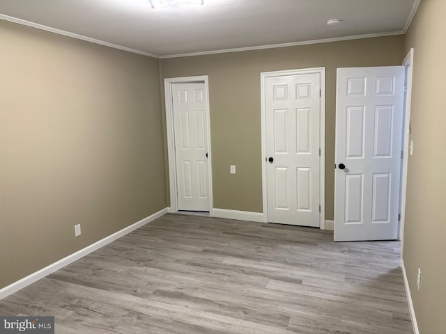unfurnished bedroom with wood finished floors, baseboards, and ornamental molding