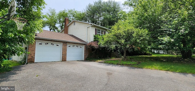 30120 Dudley Rd, Mechanicsville, MD 20659 - view of side of property featuring a garage, asphalt driveway, brick siding, and a chimney