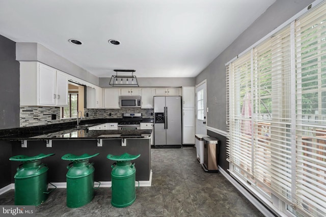 12329 Manchester Way, Woodbridge, VA 22192 - kitchen with stainless steel appliances, a peninsula, dark countertops, white cabinets, and decorative backsplash