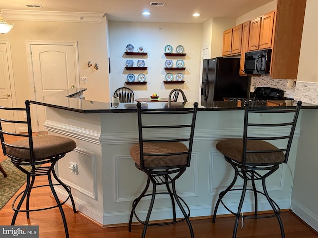 902 Macphail Woods Xing Unit 4F, Bel Air, MD 21015 - kitchen with black appliances, a breakfast bar area, wood finished floors, a peninsula, and tasteful backsplash
