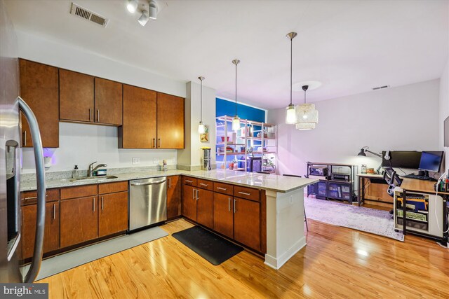 8005 13th St Unit 411, Silver Spring, MD 20910 - kitchen with stainless steel appliances, light wood finished floors, a sink, a peninsula, and hanging light fixtures