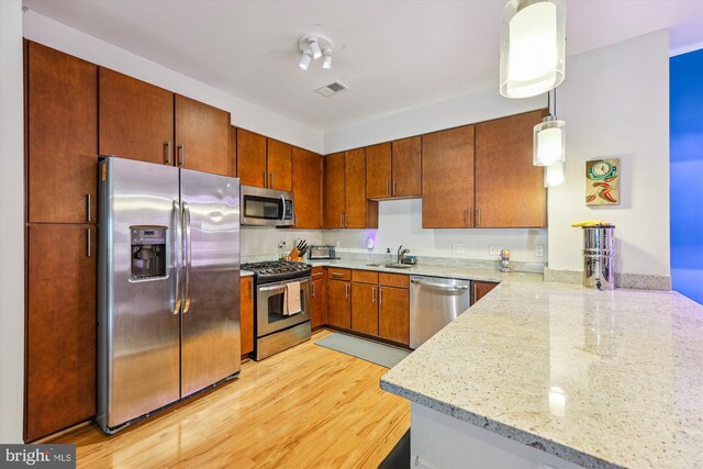 8005 13th St Unit 411, Silver Spring, MD 20910 - kitchen featuring appliances with stainless steel finishes, a sink, a peninsula, light stone counters, and brown cabinetry