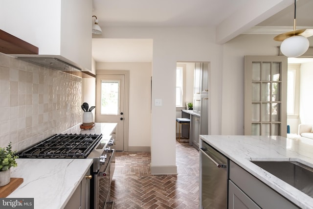 110 Varnum St NW, Washington, DC 20011 - kitchen featuring stainless steel appliances, decorative backsplash, wall chimney exhaust hood, gray cabinetry, and light stone counters