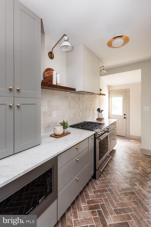 110 Varnum St NW, Washington, DC 20011 - kitchen featuring high end stove, gray cabinetry, decorative backsplash, light stone counters, and brick flooring