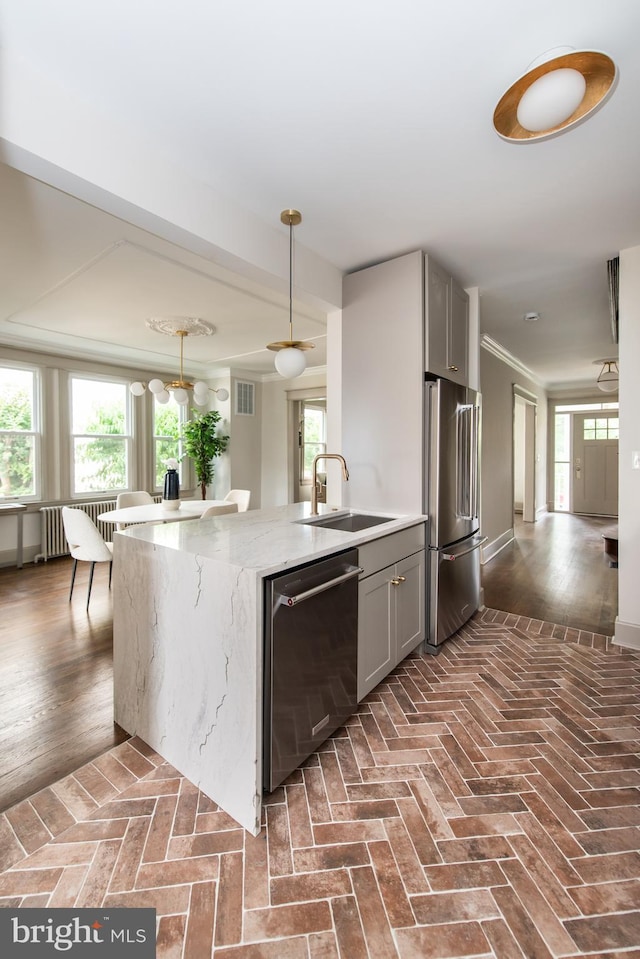 110 Varnum St NW, Washington, DC 20011 - kitchen featuring appliances with stainless steel finishes, a sink, gray cabinetry, light stone counters, and brick flooring