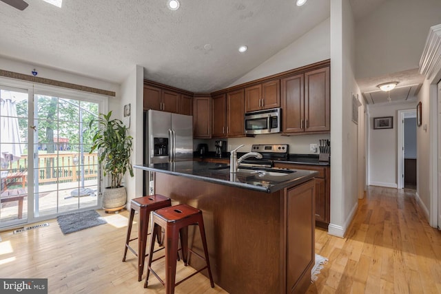6402 Devonshire Ln, Frederick, MD 21703 - kitchen featuring appliances with stainless steel finishes, light wood finished floors, a kitchen breakfast bar, a sink, and a textured ceiling