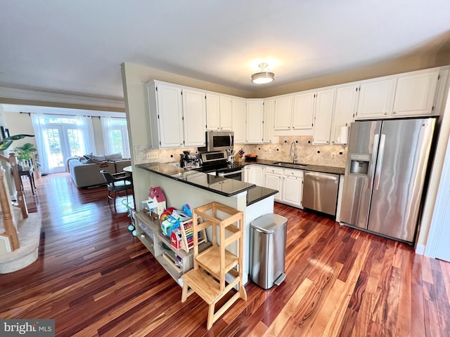 1310 Sundial Dr, Reston, VA 20194 - kitchen with appliances with stainless steel finishes, dark countertops, dark wood-type flooring, white cabinets, and tasteful backsplash