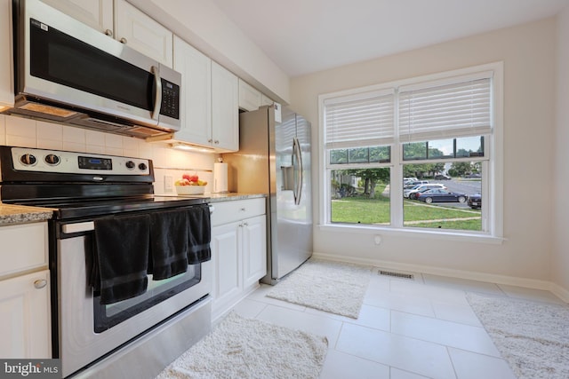 17455 Kagera Dr, Dumfries, VA 22025 - kitchen with stainless steel appliances, baseboards, white cabinetry, and tasteful backsplash