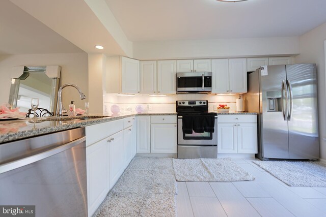 17455 Kagera Dr, Dumfries, VA 22025 - kitchen featuring stainless steel appliances, a sink, light stone counters, white cabinets, and recessed lighting