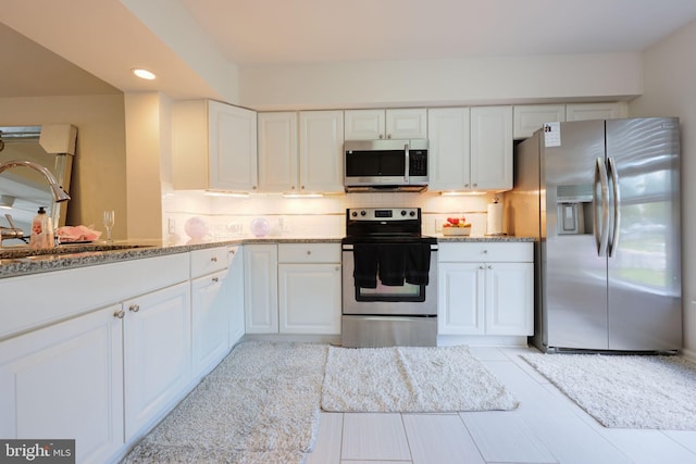 17455 Kagera Dr, Dumfries, VA 22025 - kitchen featuring stainless steel appliances, white cabinetry, backsplash, a sink, and light stone counters