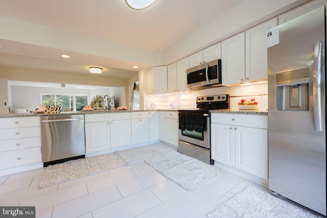 17455 Kagera Dr, Dumfries, VA 22025 - kitchen featuring stainless steel appliances, backsplash, white cabinetry, light stone counters, and recessed lighting