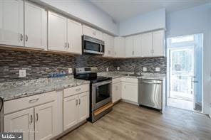 1743 E Oliver St, Baltimore, MD 21213 - kitchen with stainless steel appliances, tasteful backsplash, and white cabinets