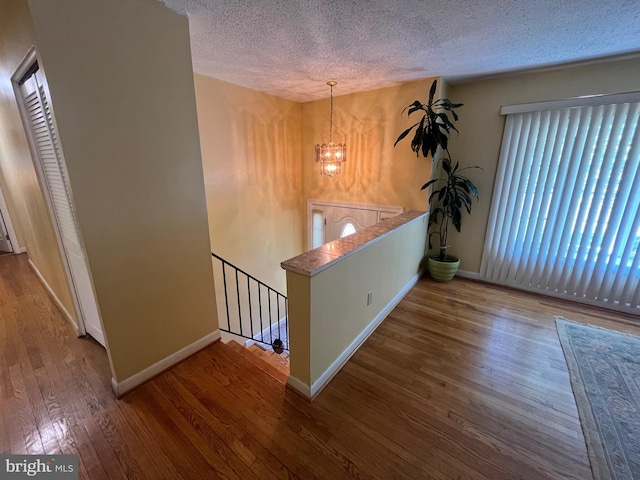 7001 Kepner Ct, Lanham, MD 20706 - hall featuring an upstairs landing, a textured ceiling, wood finished floors, baseboards, and a chandelier