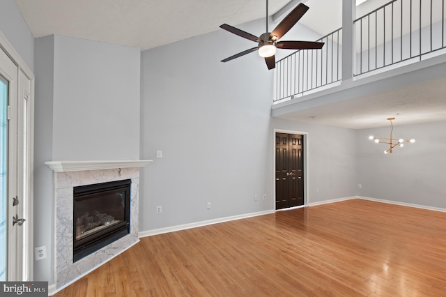 2000 Phillips Ter Unit 12, Annapolis, MD 21401 - unfurnished living room featuring wood finished floors, a glass covered fireplace, high vaulted ceiling, a ceiling fan, and a chandelier