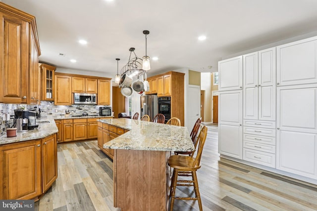 148 Ryans Run, Sicklerville, NJ 08081 - kitchen featuring appliances with stainless steel finishes, a breakfast bar area, brown cabinetry, light wood finished floors, and backsplash