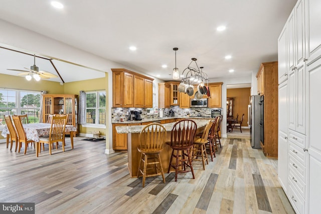 148 Ryans Run, Sicklerville, NJ 08081 - kitchen with appliances with stainless steel finishes, light wood-style flooring, a center island, brown cabinetry, and light stone countertops