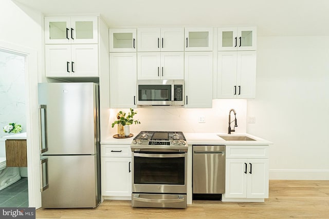 2517 Ontario Rd NW Unit 5, Washington, DC 20009 - kitchen with appliances with stainless steel finishes, a sink, light wood finished floors, white cabinetry, and light countertops