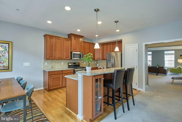 21623 Romans Dr, Ashburn, VA 20147 - kitchen featuring stainless steel appliances, brown cabinets, light stone counters, tasteful backsplash, and recessed lighting