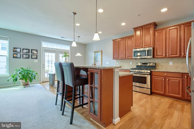 21623 Romans Dr, Ashburn, VA 20147 - kitchen with stainless steel appliances, brown cabinets, recessed lighting, a breakfast bar area, and a center island