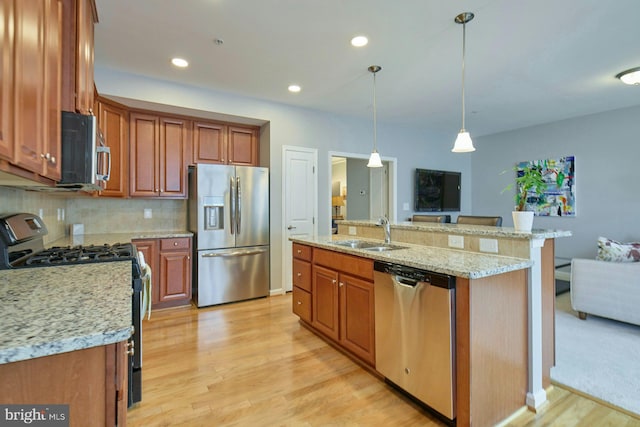 21623 Romans Dr, Ashburn, VA 20147 - kitchen featuring appliances with stainless steel finishes, a sink, light wood-style floors, brown cabinets, and recessed lighting