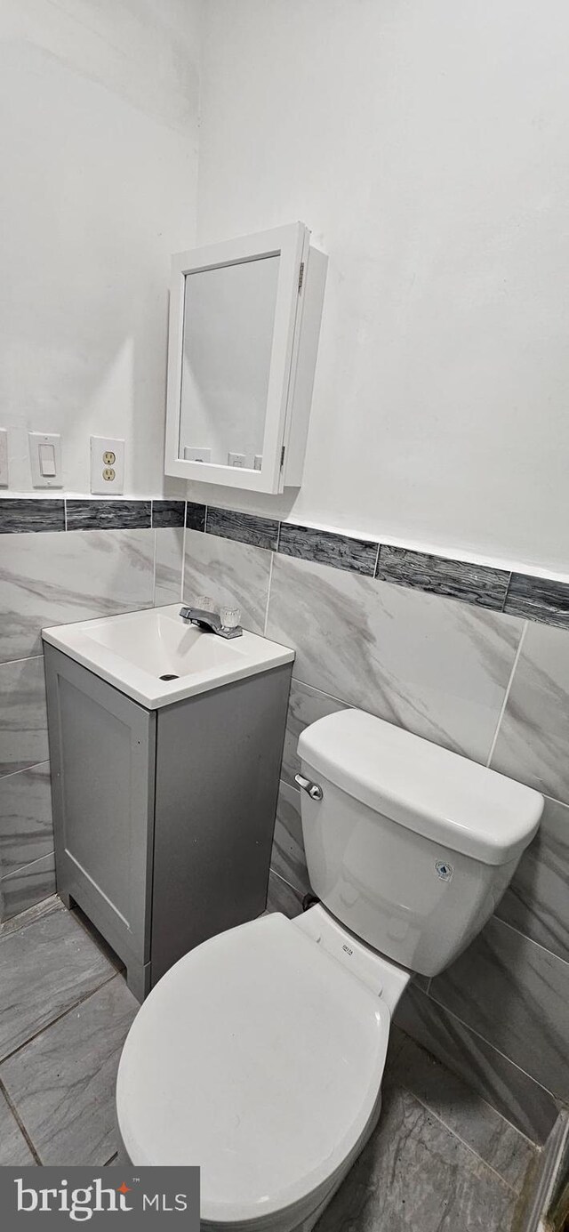 2540 W Silver St, Philadelphia, PA 19132 - bathroom with tile walls, vanity, toilet, and wainscoting