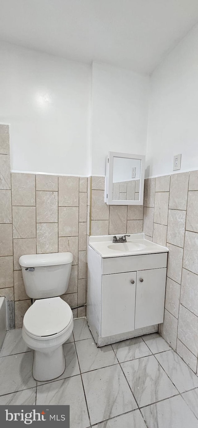 2540 W Silver St, Philadelphia, PA 19132 - bathroom with tile walls, vanity, toilet, marble look tiles, and wainscoting