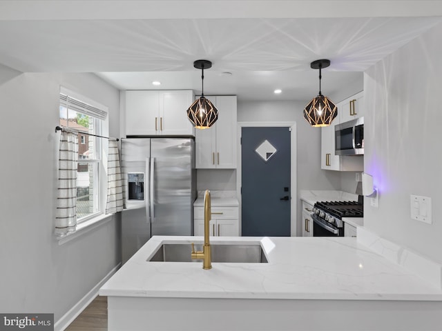 610 Galveston Pl SE, Washington, DC 20032 - kitchen with stainless steel appliances, a sink, white cabinets, hanging light fixtures, and light stone countertops