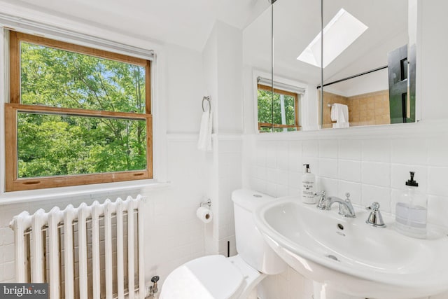 2937 Fort Baker Dr SE, Washington, DC 20020 - bathroom featuring radiator heating unit, tile walls, toilet, a skylight, and a sink