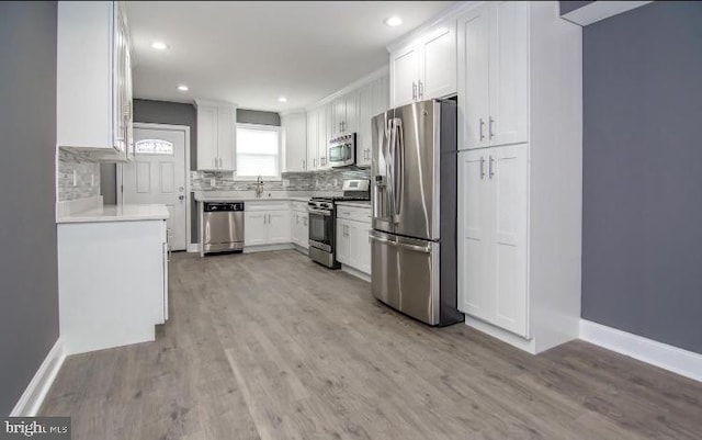 119 S Conkling St, Baltimore, MD 21224 - kitchen featuring appliances with stainless steel finishes, light wood-style floors, white cabinets, decorative backsplash, and light countertops