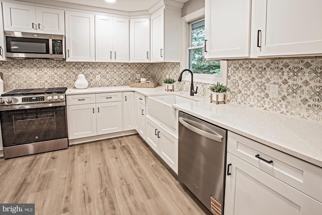 118 Bock Ave, Wenonah, NJ 08090 - kitchen with stainless steel appliances, a sink, light wood-style flooring, white cabinets, and decorative backsplash