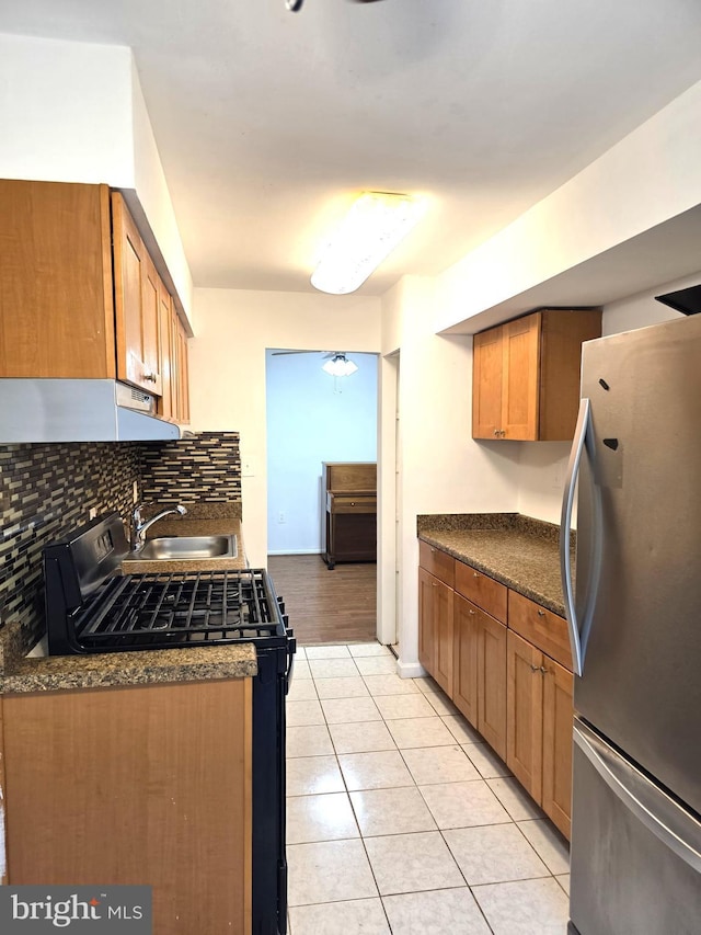 3376 Woodburn Rd, Annandale, VA 22003 - kitchen featuring appliances with stainless steel finishes, under cabinet range hood, dark countertops, light tile patterned flooring, and backsplash