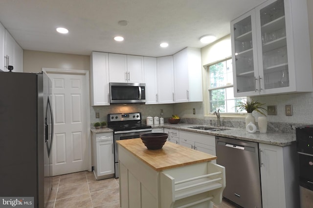 8307 Satinleaf Ct, Bowie, MD 20715 - kitchen featuring appliances with stainless steel finishes, butcher block countertops, tasteful backsplash, white cabinetry, and glass insert cabinets