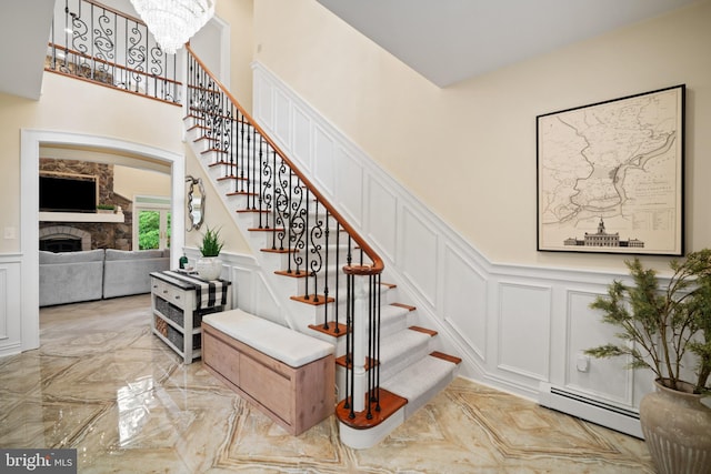 14 Waterfront Way, Hammonton, NJ 08037 - stairway with a decorative wall, a baseboard heating unit, a fireplace, wainscoting, and a chandelier