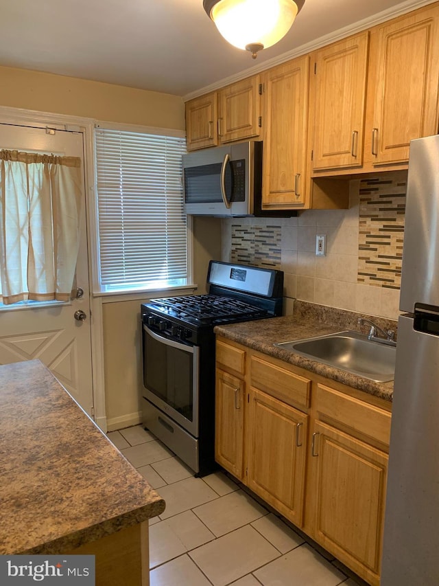3918 Dudley Ave, Baltimore, MD 21213 - kitchen with appliances with stainless steel finishes, a sink, light tile patterned floors, dark countertops, and decorative backsplash