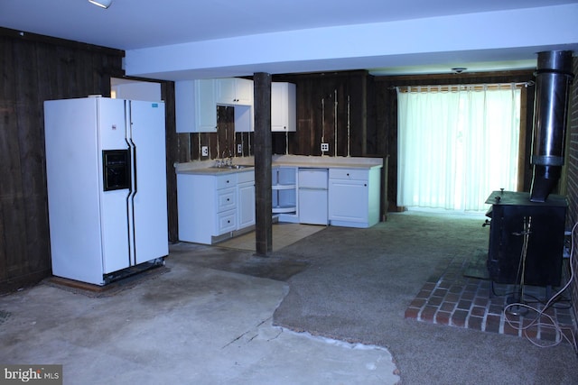 8406 Rainbow Bridge Ln, Springfield, VA 22153 - kitchen with white refrigerator with ice dispenser, fridge, a wood stove, white cabinets, and wood walls