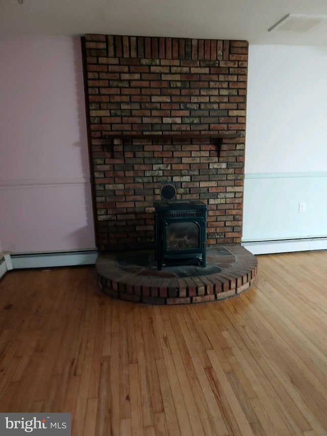 612 Deerhead Lake Dr, Forked River, NJ 08731 - detailed view of a baseboard heating unit, wood finished floors, and a wood stove