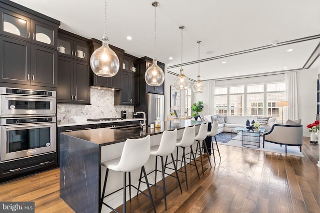 1741 Mckenna Point Dr Unit 2701, Mclean, VA 22102 - kitchen featuring stainless steel appliances, open floor plan, backsplash, an island with sink, and a breakfast bar area